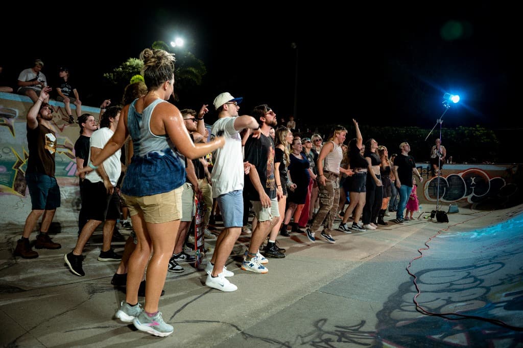 Crowd gathered in the lit skate bowl at night