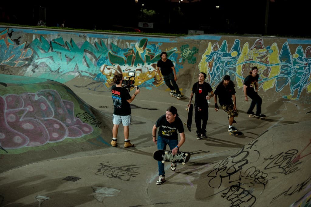 Camera operator filming skateboarders in the graffiti bowl